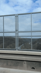 Highway view with metal fence recorded from moving vehicle