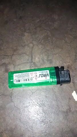 The video shows a green Viroj lighter being flicked once. The lighter is on a gray, cracked surface.