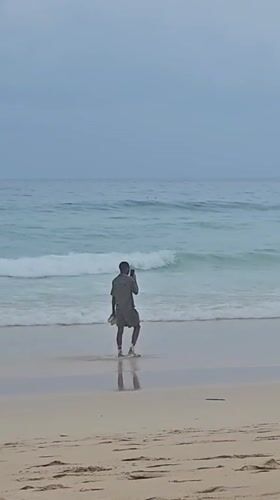 Overcast morning at Karon Beach, flags up, people in the water