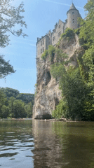 Kayakers paddle Lesse River below medieval Walzin Castle, Belgium