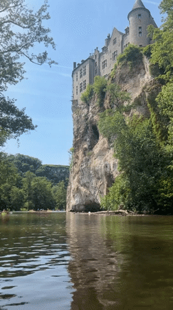 Kayakers paddle Lesse River below medieval Walzin Castle, Belgium