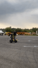 Motorcycle and ATV stunt show with drifting car, crowd watching.