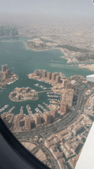 Passenger films aerial views of Doha during morning flight