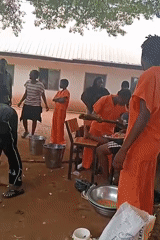 Community cooking operation with large pots over open fires in Uko
