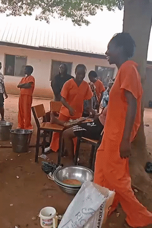 Community cooking operation with large pots over open fires in Uko
