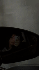Woman takes selfie reflected in moving car mirror