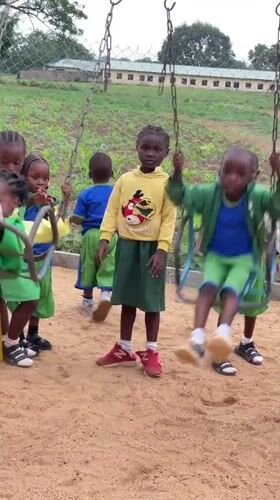 Children play on swings at Akwanga playground
