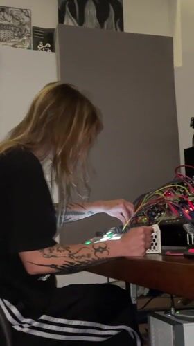 Tattooed musician works electronic setup in La Lucila studio