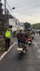 Police officer directs motorcycle traffic at Denpasar crosswalk