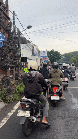 Police officer directs motorcycle traffic at Denpasar crosswalk