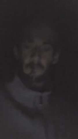 A person lights a cigarette in a dark environment. The person is wearing a hoodie. The video is grainy and poorly lit.