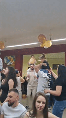 Party celebration features children on shoulders with balloons, dancing