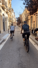 Two cyclists ride through Barcelona streets and park