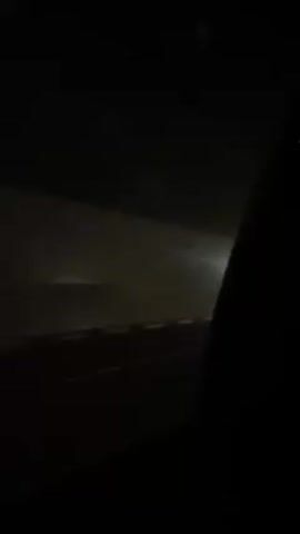 A car is driving through a tunnel at night. The view is from inside the car, through the window, showing the tunnel walls and the road passing by. The car's exterior is briefly visible. There is a light inside the tunnel.