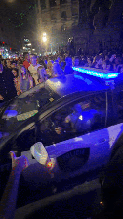 Crowd surrounds police car with flashing lights in Buenos Aires