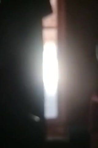 The video captures a dimly lit interior with a bright light source visible in the center, likely a window. The image is grainy and out of focus. Two dark shapes, possibly furniture or curtains, frame the central light. No individuals or specific objects are clearly discernible. The timestamp indicates the video spans from 00:00 to 00:03.