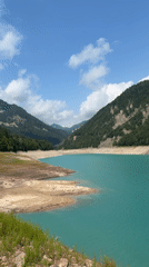 Low-water alpine lake in the Dolomites on a clear summer morning