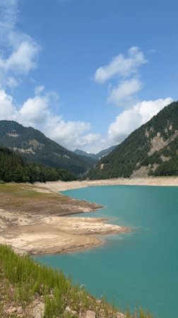 Low-water alpine lake in the Dolomites on a clear summer morning