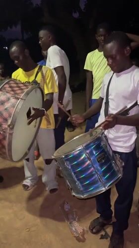 Young men play drums in evening gathering, Andaha Nigeria
