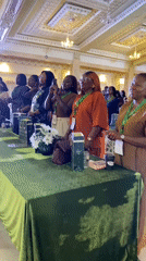 Lanyarded attendees gather around a green velvet table at a formal event
