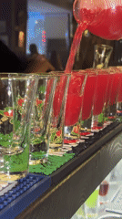 Red liquid poured into festive shot glasses at Russian bar
