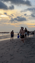 Beachgoer walks toward ocean during golden sunset in North Kuta