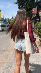Woman in plaid shirt walks streets of Baan Bang Rak