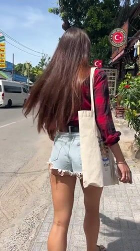 Woman in plaid shirt walks streets of Baan Bang Rak