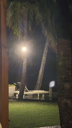 Nighttime rainfall captured near palm trees in Karangasem, Indonesia