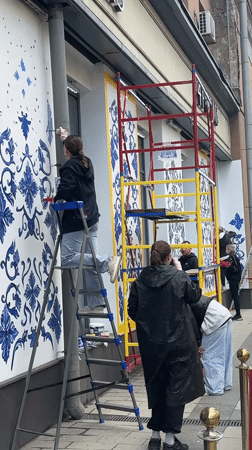 Women paint floral murals on Moscow storefronts near Planetarium
