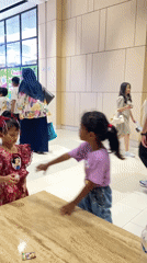 Two girls stand together at Surabaya shopping mall table