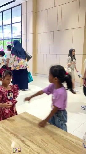 Two girls stand together at Surabaya shopping mall table