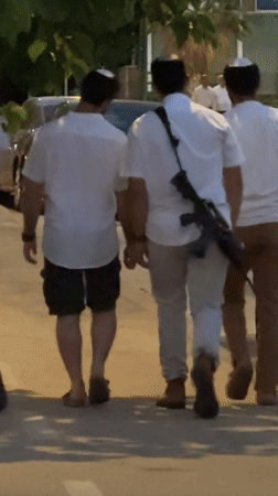 Armed pedestrians in kippahs walking a Netanya sidewalk