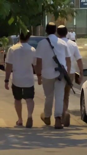 Armed pedestrians in kippahs walking a Netanya sidewalk