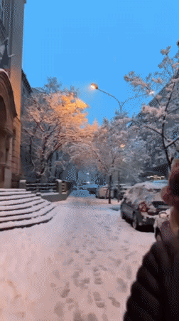 Winter pedestrian walks snowy Belgrade street during evening hours