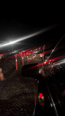 Cars queue at night in Indio with traffic control