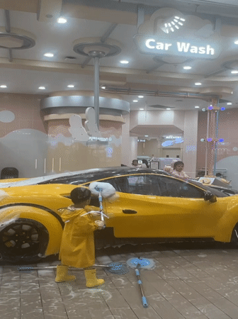Kids scrub a foam-covered toy car at NEOBIO play center, Liangjiang