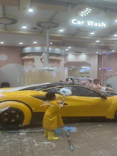 Kids scrub a foam-covered toy car at NEOBIO play center, Liangjiang