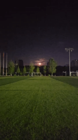 Full moon rises over a floodlit soccer field in Chongqing