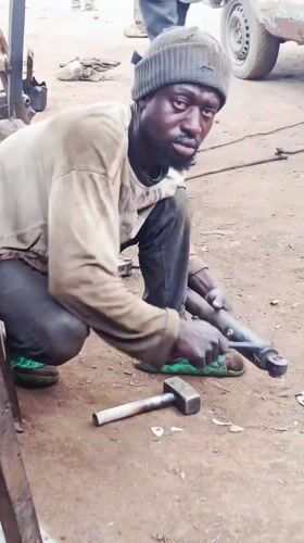 Auto mechanics work at informal roadside workshop in Nigeria
