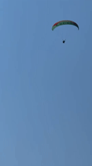 Paraglider floats over Fethiye's mountain landscape on a clear day