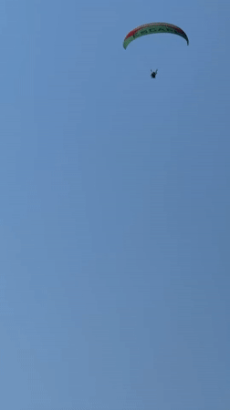 Paraglider floats over Fethiye's mountain landscape on a clear day