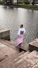 Woman in period dress walks waterfront steps in Saint Petersburg