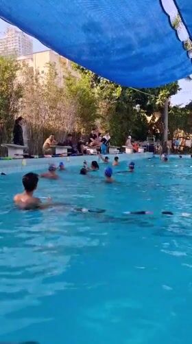 Swimmers train in a shaded outdoor lap pool in Nha Trang