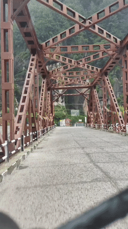 Red truss bridge cuts across a rocky gorge in Kulang