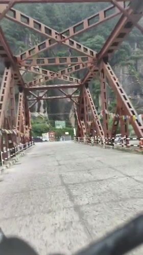 Red truss bridge cuts across a rocky gorge in Kulang