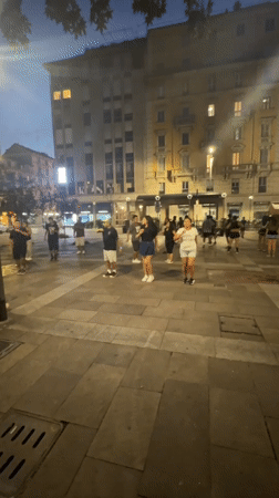 Synchronized group dancing in a Milan square at dusk