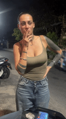 Woman smoking cigarette near motorcycle in North Kuta
