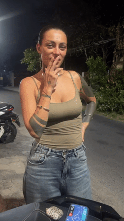 Woman smoking cigarette near motorcycle in North Kuta