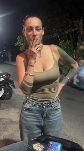 Woman smoking cigarette near motorcycle in North Kuta